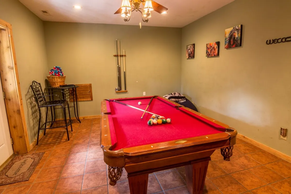 This image features a recreation room with a pool table, bar stools, and colorful artwork on the wall. The space exudes a playful and relaxed atmosphere, perfect for socializing and friendly games.